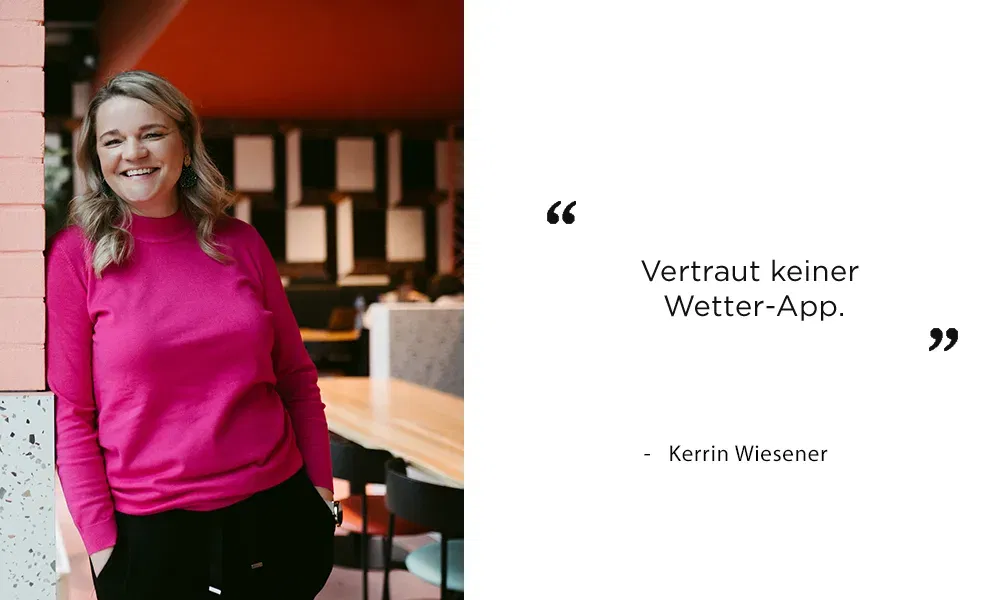 Kerrin Wiesener lehnt lächelnd an einer Wand und gibt einen witzigen Ratschlag zur Wetterplanung für Hochzeiten.