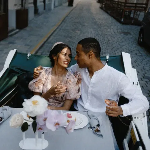 Romantisches Paar genießt ein intimes Dinner in einer malerischen Kutsche mit elegant gedecktem Tisch und blühenden Blumen.