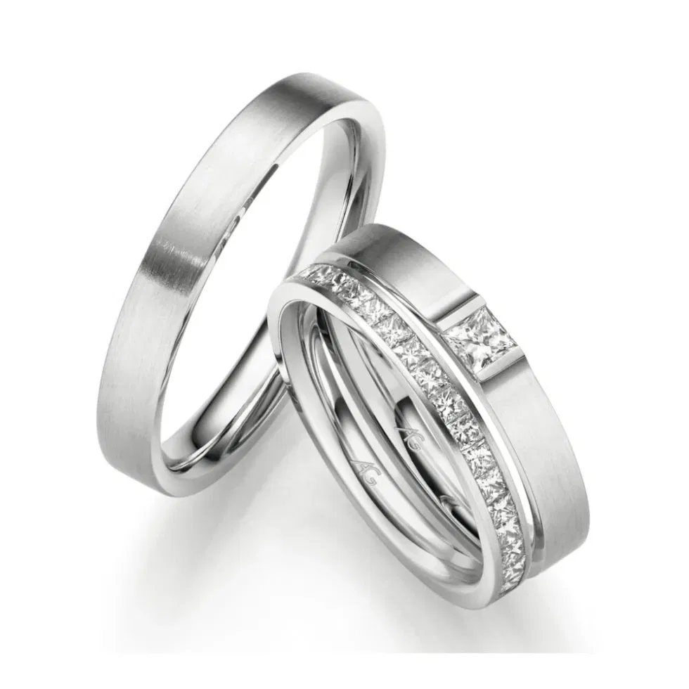Zwei mattierte Eheringe aus Platin mit modernen Diamantfassungen, darunter ein Ring mit Prinzessschliff und seitlicher Steinreihe.