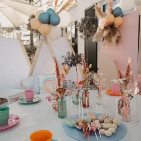 Farbenfrohe Tischdekoration für eine Gartenparty mit Boho-Elementen, Trockenblumen und bunten Tellern, ideal für Kinder oder sommerliche Feiern.