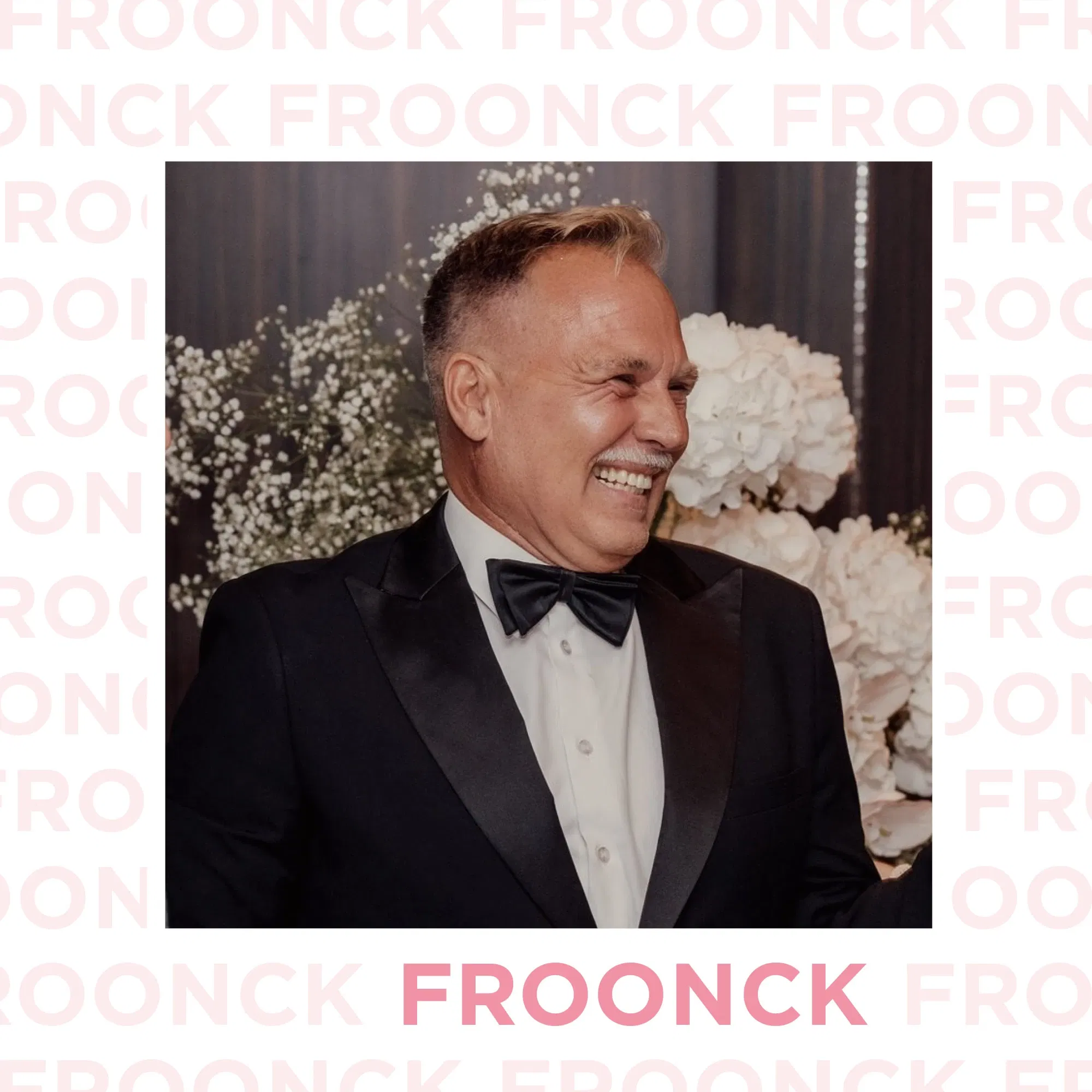 Froonck in elegantem Smoking, lachend vor einem Hintergrund mit weißen Blumenarrangements – ein Hochzeitsprofi mit Stil und Charisma