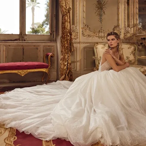 Elegante Braut in einem luxuriösen Prinzessinnenkleid mit langer Schleppe in einem historischen Schlossambiente.