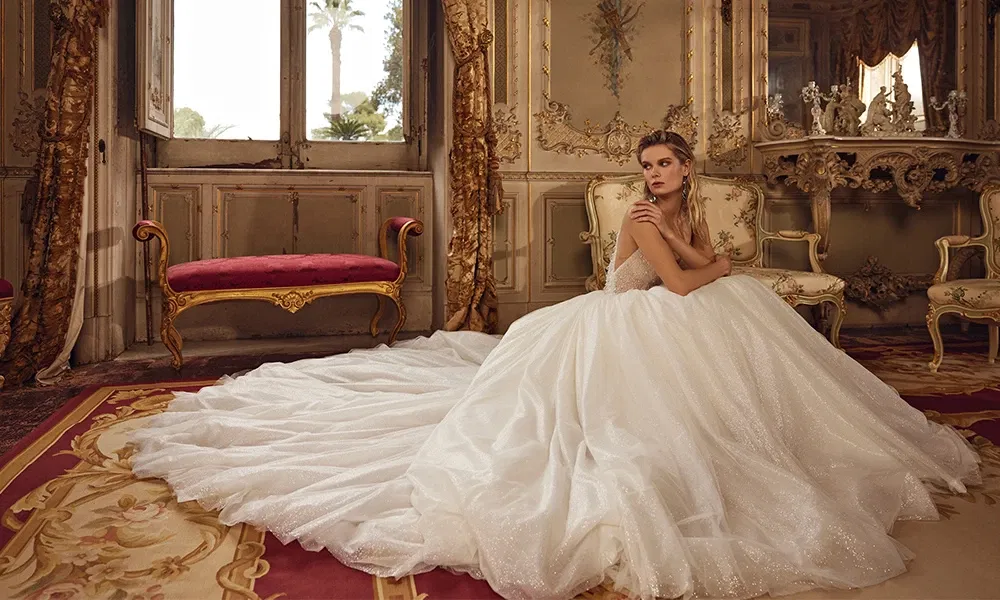 Elegante Braut in einem luxuriösen Prinzessinnenkleid mit langer Schleppe in einem historischen Schlossambiente.