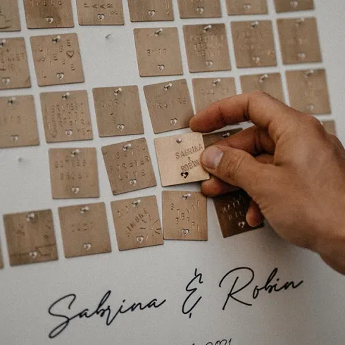 Individuelles Hochzeitsgästebuch mit gravierten Metallplättchen auf einer Tafel.