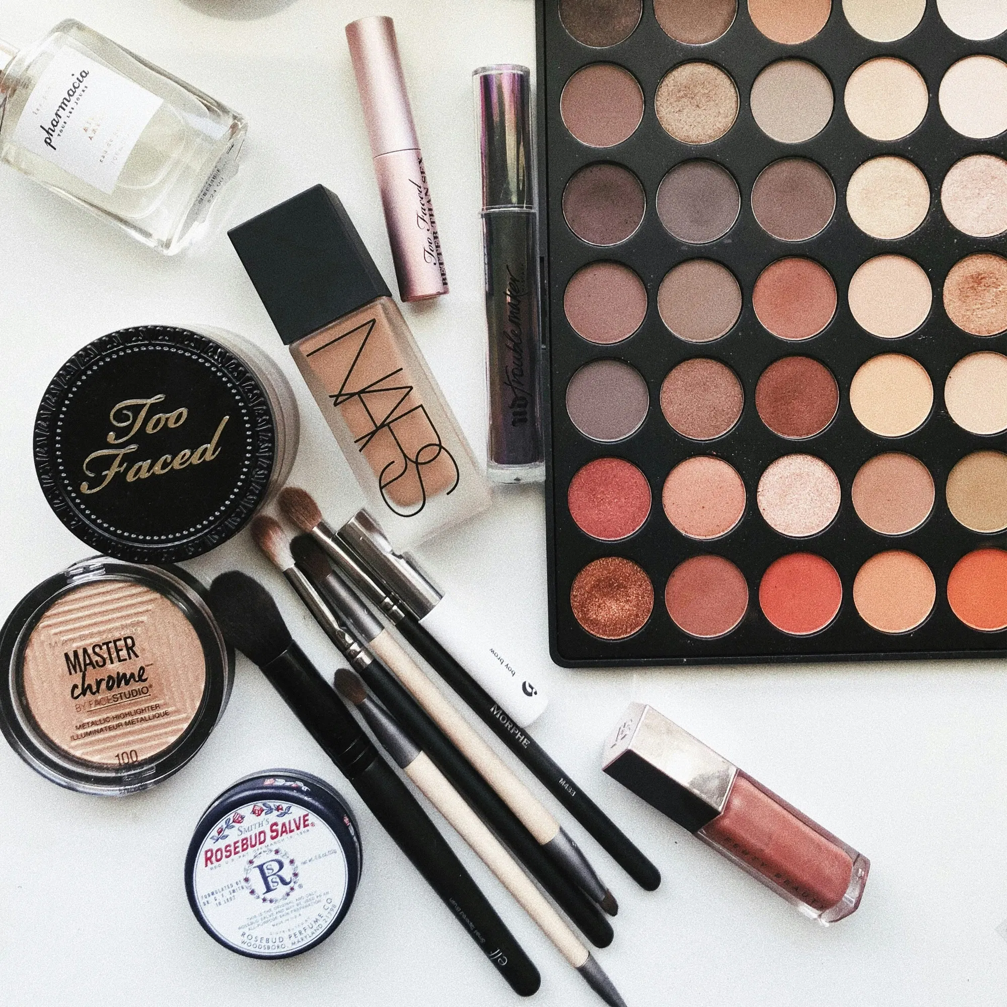 Flach gelegte Beauty-Produkte für das perfekte Braut-Make-up, inklusive Lidschattenpalette, Pinsel, Foundation und Highlighter, ideal für den Hochzeitstag.