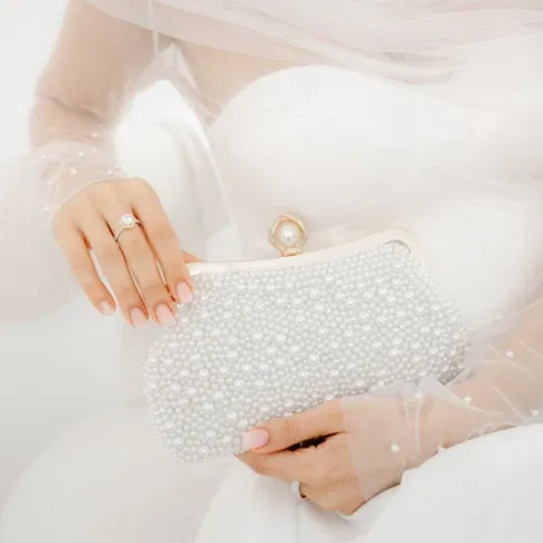 Eine Braut hält eine luxuriöse, mit Perlen besetzte Hochzeits-Clutch.