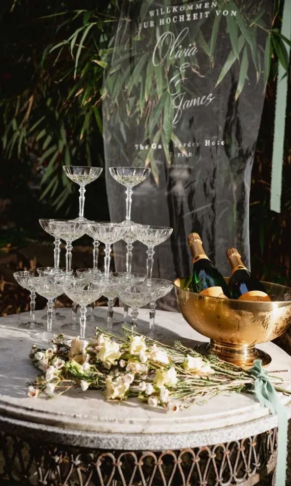 Champagnerpyramide mit Kristallgläsern und goldener Sektkühlschale als stilvolles Hochzeitsdetail im Garten.