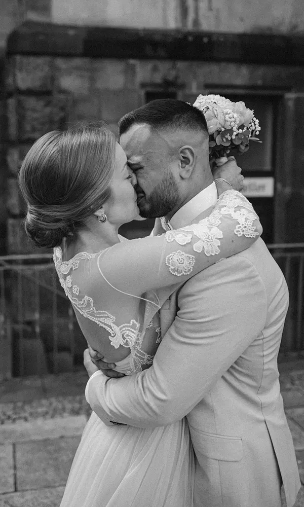 Inniger Kuss eines Brautpaars in emotionaler Schwarz-Weiß-Aufnahme.