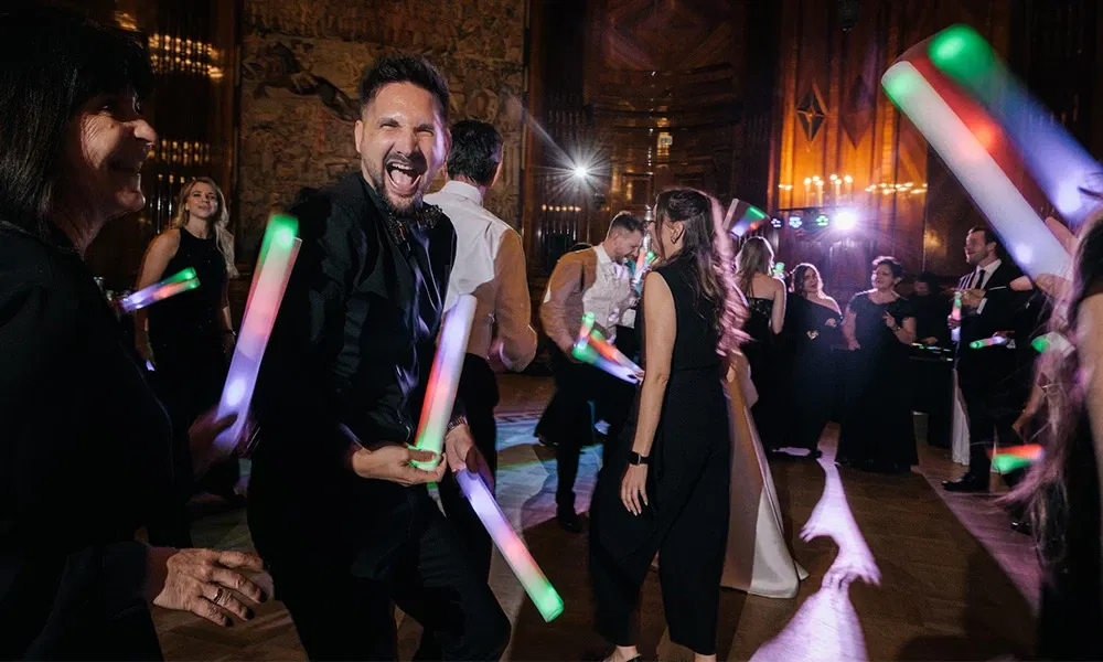 Gäste tanzen ausgelassen mit bunten Leuchtstäben auf der Hochzeitsparty.
