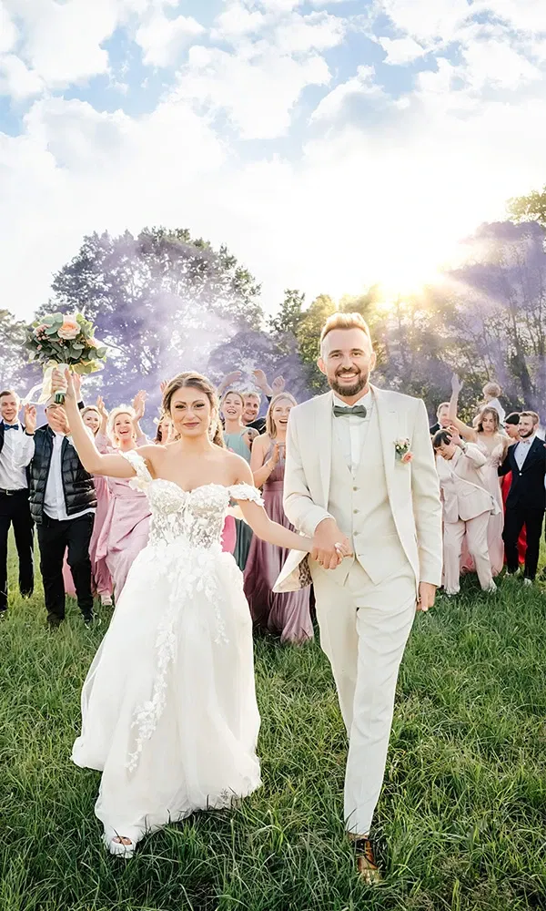 Braut und Bräutigam ziehen fröhlich mit ihren Gästen ein.
