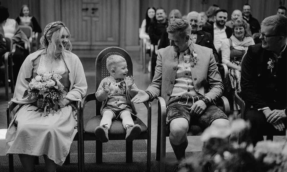 Kleiner Junge gibt seinem Vater ein High Five während der Trauung im Standesamt.