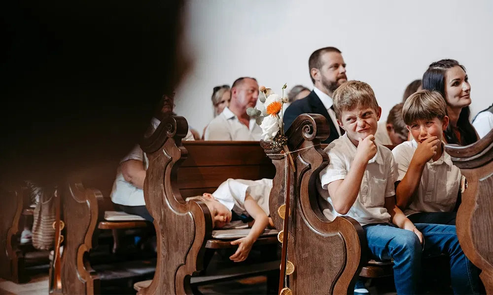 Zwei Jungs schneiden Grimassen während eines langen Traugottesdienstes.