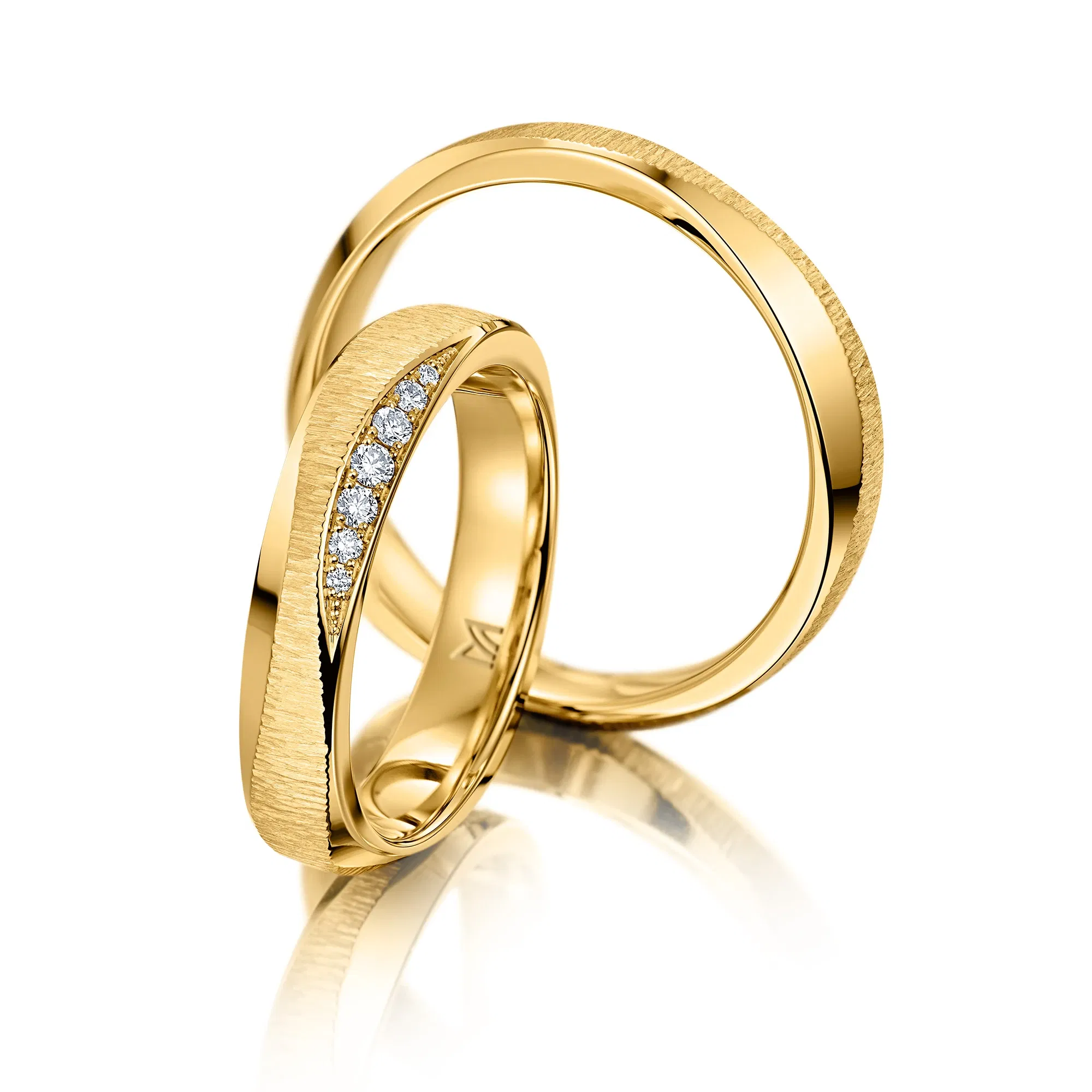 Gelbgoldene Eheringe mit strukturierter Oberfläche und seitlichem Edelsteinbesatz.