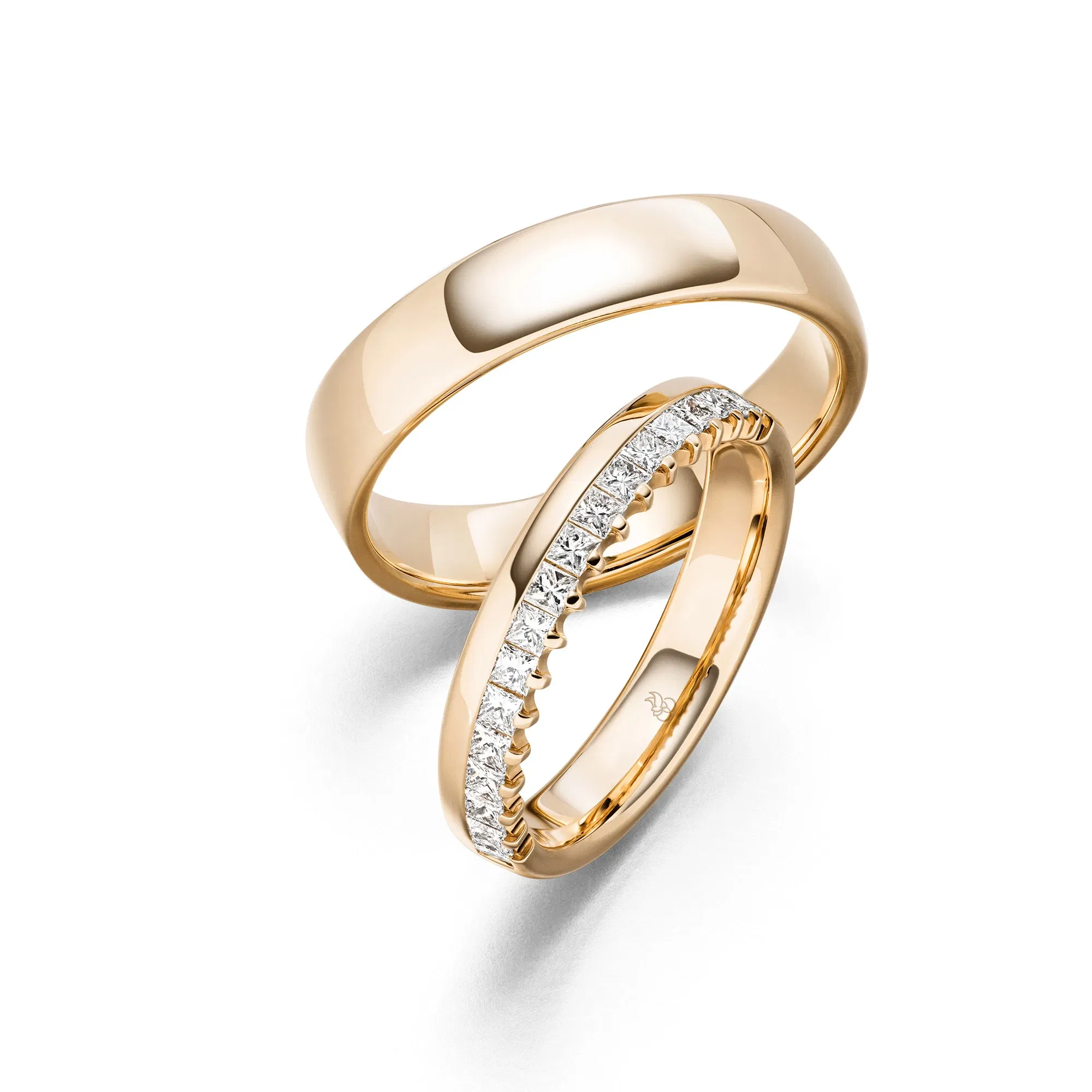 Klassische Trauringe aus Gelbgold, einer mit funkelnden Brillanten rundum gefasst.