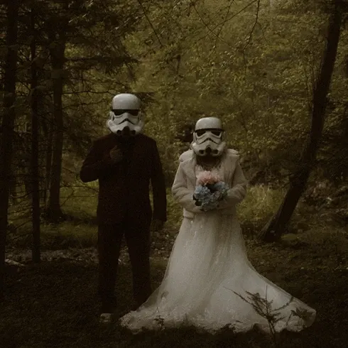 Hochzeitspaar mit Stormtrooper-Helmen posiert im düsteren Wald