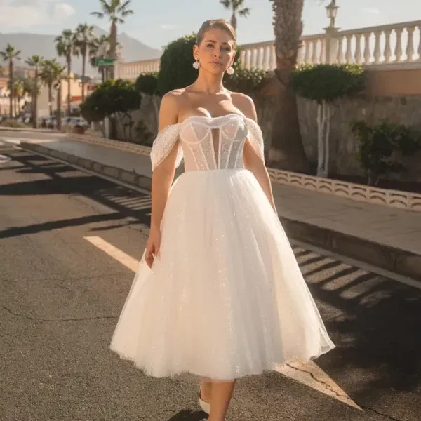 Braut in schulterfreiem Tea-Length-Kleid mit Tüllrock und Corsagen-Oberteil auf sonniger Straße mit Palmen