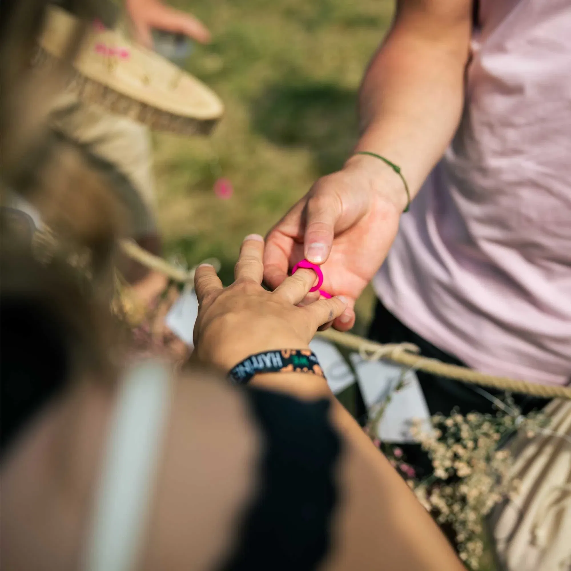 Festivalromantik pur: Ein pinker Symbolring wird liebevoll bei einer freien Trauung auf dem Happiness Festival angesteckt.