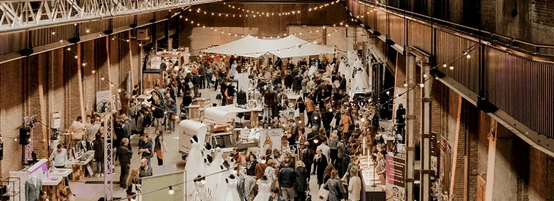 Belebte Hochzeitsmesse in einer Industriehalle mit festlicher Beleuchtung