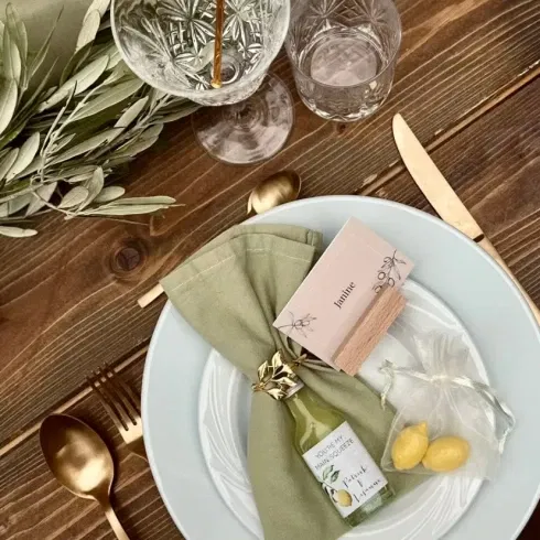 Stilvoll gedeckter Hochzeitstisch mit goldenem Besteck, olivgrüner Serviette und Zitronen-Details