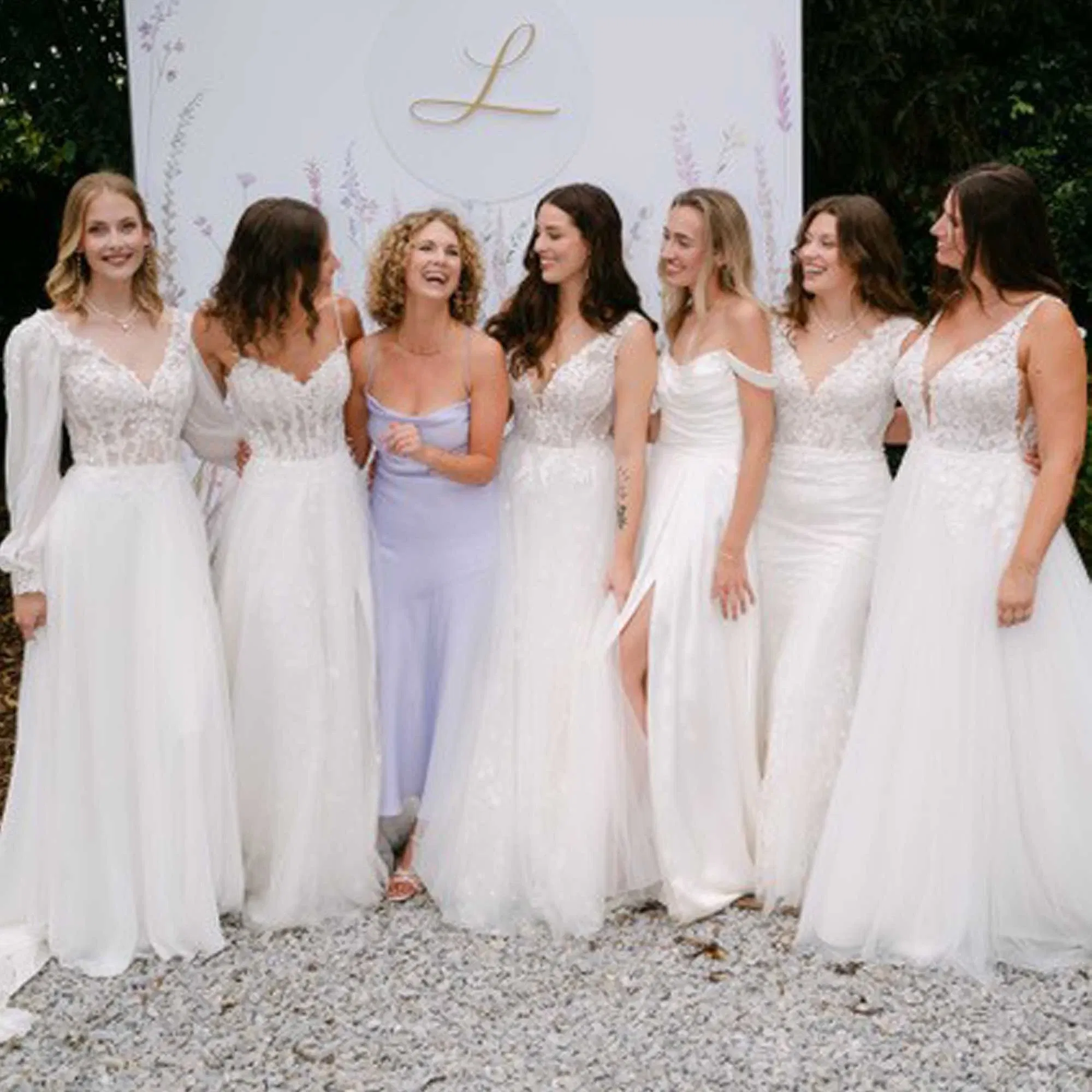 Designerin Sanna Lindström steht lächelnd mit sechs Models in weißen Brautkleidern vor dem Logo der „Villa Lindström“.