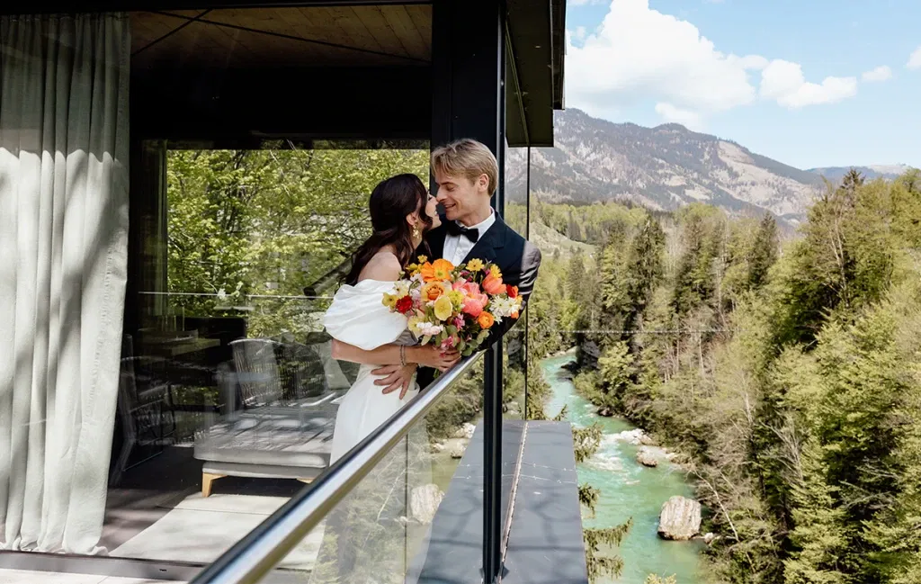 Brautpaar auf modernem Balkon mit Blick auf grüne Berge – Symbol einer eleganten Nature Wedding.