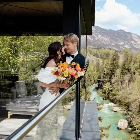 Brautpaar auf modernem Balkon mit Blick auf grüne Berge – Symbol einer eleganten Nature Wedding.