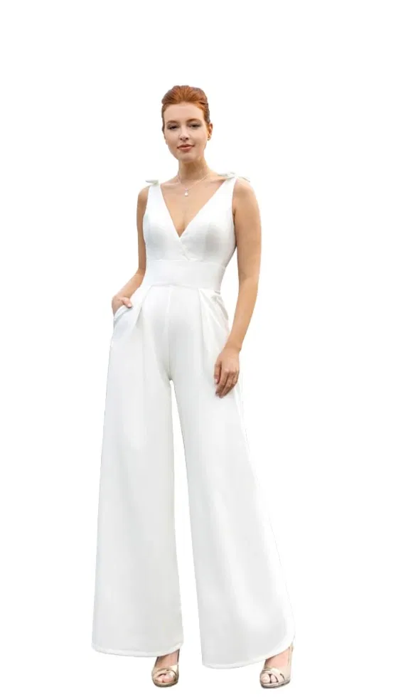 Brautmodell trägt einen modernen Braut-Jumpsuit mit tiefem V-Ausschnitt, breitem Taillenbund und weit geschnittenen Hosenbeinen, minimalistisch inszeniert vor weißem Hintergrund.
