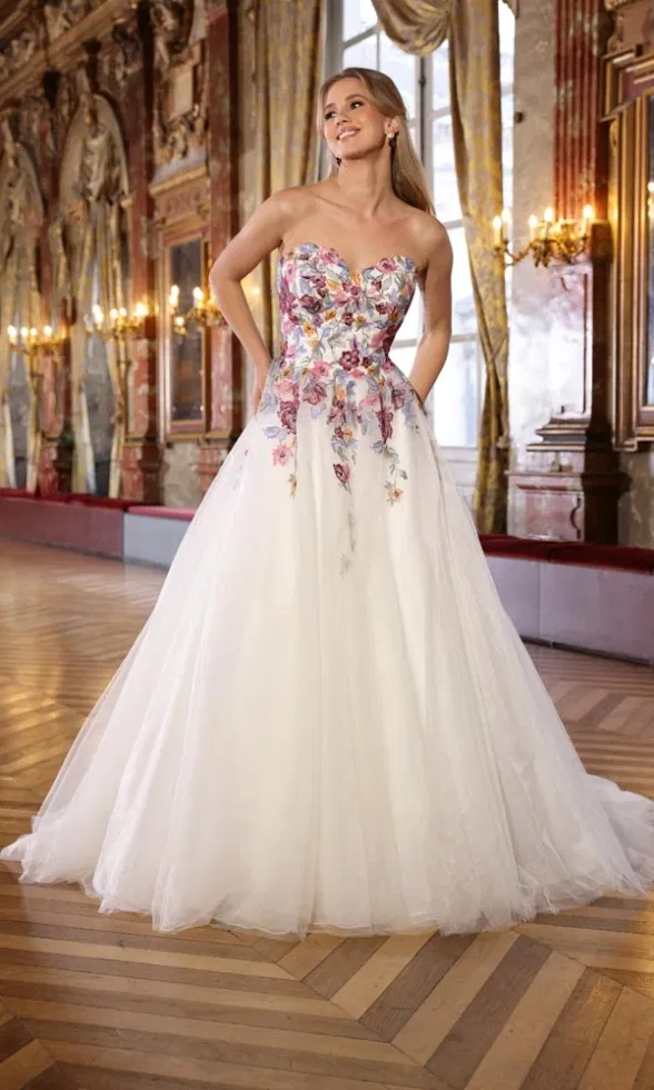 Tülliges Ballkleid mit farbenfrohem, besticktem Oberteil und großem Rock, fotografiert in einem prunkvollen Saal.