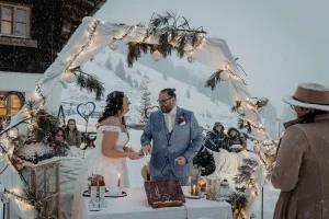 Winterliche Outdoor-Hochzeit im Schnee mit romantisch dekoriertem Traubogen, Lichterketten und gemütlicher Atmosphäre.