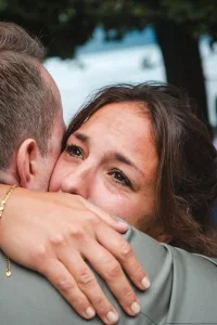 Emotionale Braut umarmt ihren Partner innig, während ihr Tränen der Freude über die Wange laufen.