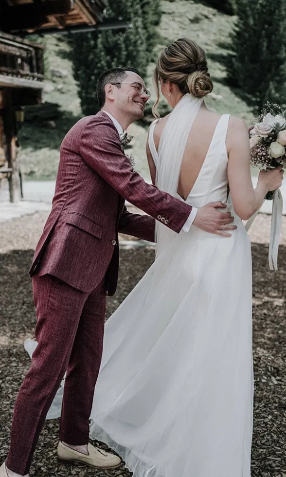 Berührender First-Look-Moment: Der Bräutigam legt der Braut die Hand auf den Rücken, während sie sich im fließenden Brautkleid zu ihm wendet.
