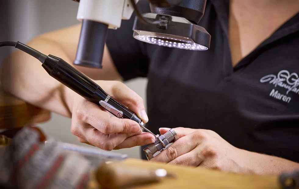 Präzise Handarbeit in der EGF Manufaktur: Eine erfahrene Fasserin setzt einen Diamanten in einen Trauring ein.