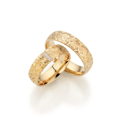 Strukturierte Fischer Trauringe aus Gelbgold mit geometrischer Oberfläche und Diamantbesatz im Damenring.