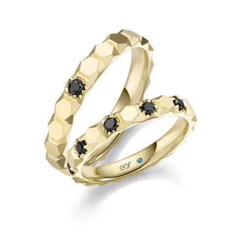 Modernes Trauringpaar aus Gelbgold mit facettierter Oberfläche und schwarzen Diamanten aus der EGF Manufaktur.