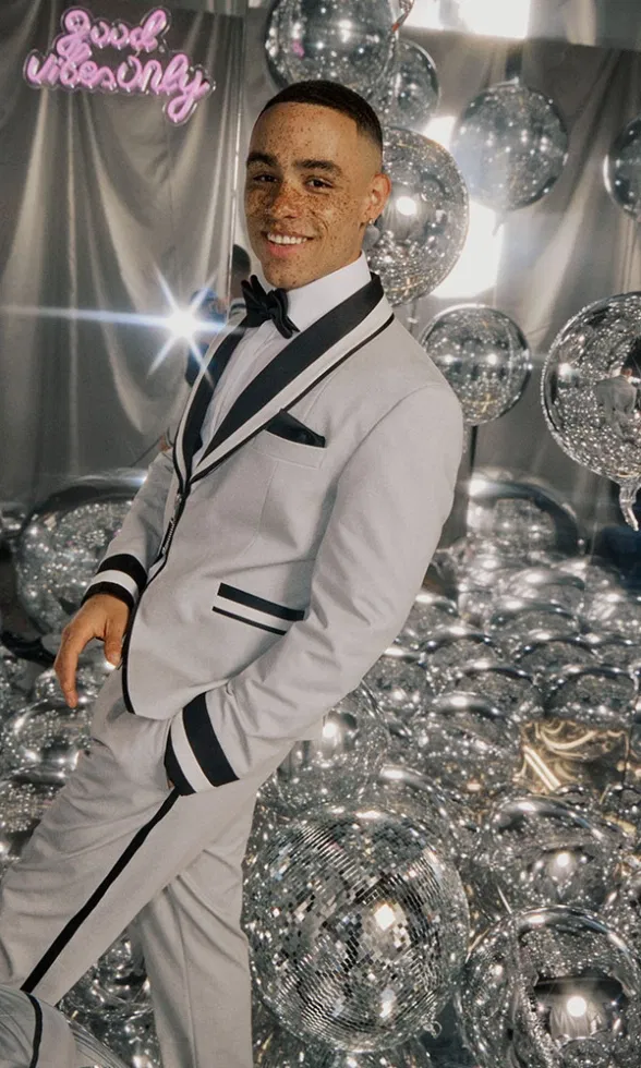 Bräutigam im modernen Smoking mit Galonstreifen, umgeben von verspiegelten Kugeln in glamouröser Partystimmung.