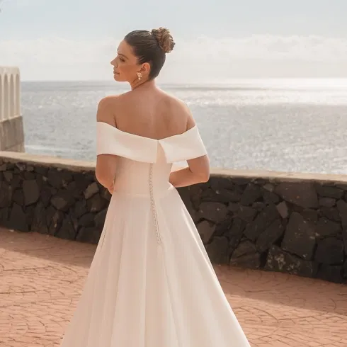 Off-Shoulder-Brautkleid von Diane Legrand mit fließendem Rock und eleganter Rückansicht am Meer.