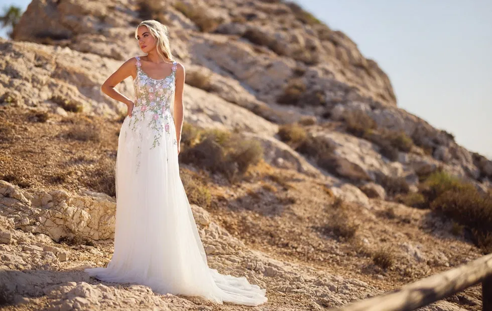 Brautkleid mit zartem, floralen Spitzenmuster und leichtem Tüllrock, inszeniert in einer felsigen Naturkulisse bei warmem Tageslicht.