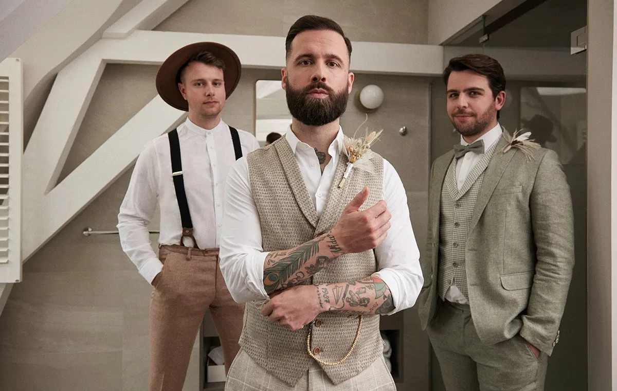 Bräutigam mit Trauzeugen in abgestimmten Anzügen kurz vor der Hochzeit, selbstbewusst und ruhig, bereit für den großen Tag.