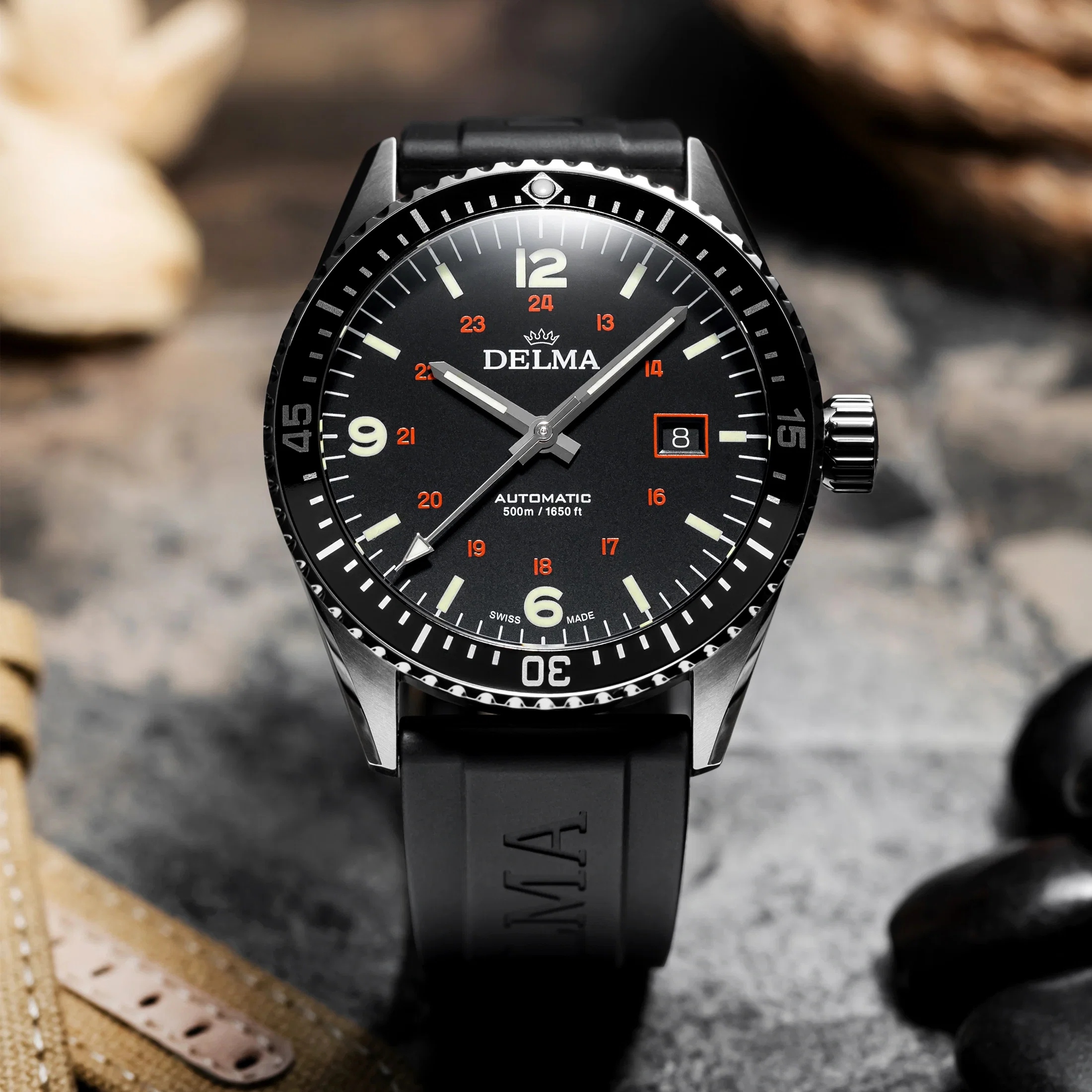 Schwarze Armbanduhr mit markantem Zifferblatt, Leuchtindizes und Datumsanzeige auf strukturiertem Untergrund