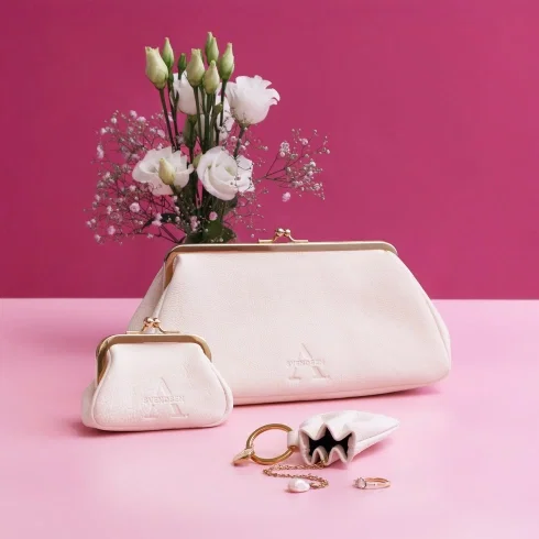Elegantes Taschen-Set von Alexandra Svendsen mit weißer Abendtasche, kleinem Schmucktäschchen und Leder-Accessoire vor pinkem Hintergrund, dekoriert mit weißen Blumen und Schmuck.