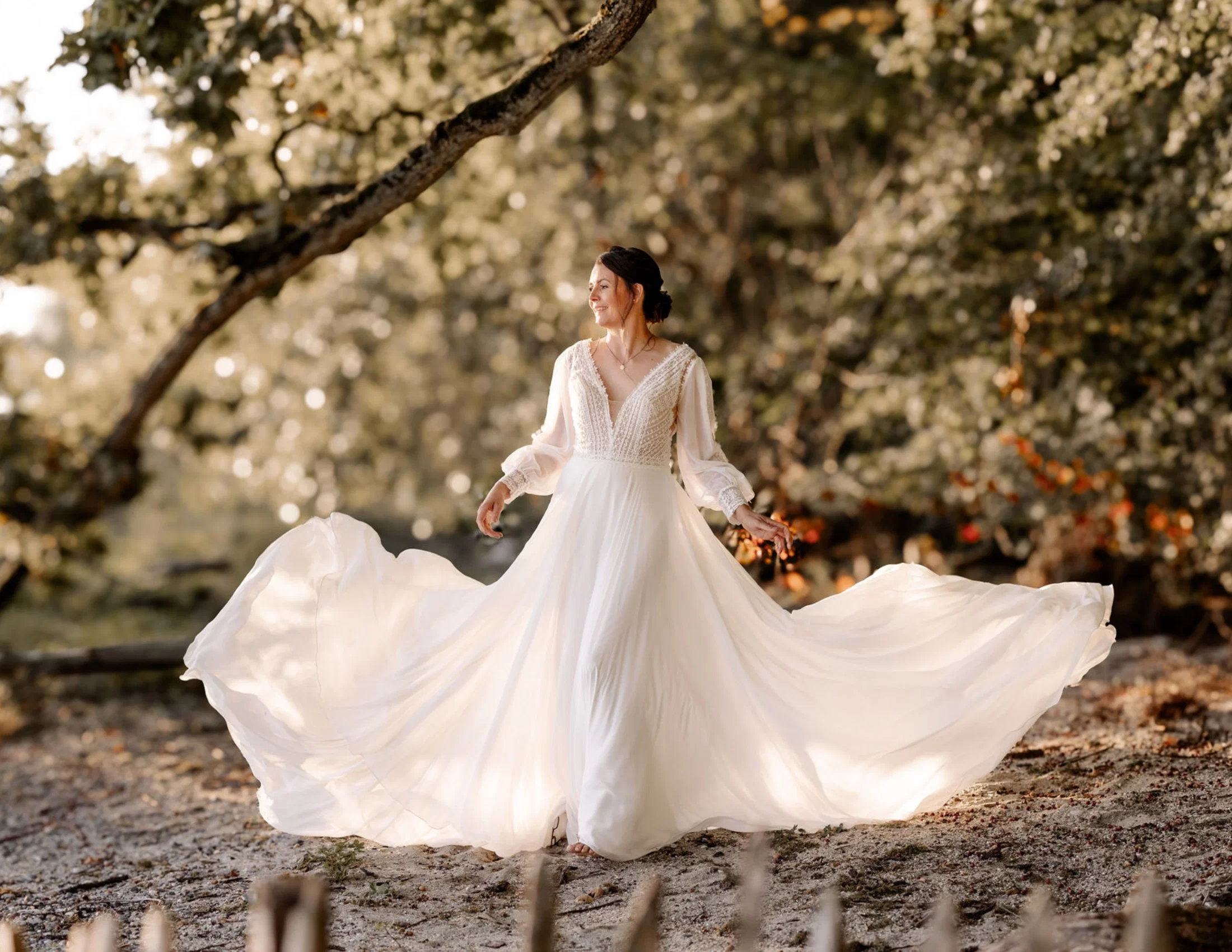 Braut im fließenden Boho-Brautkleid bei einem romantischen Brautshooting im Wald am Wasser.