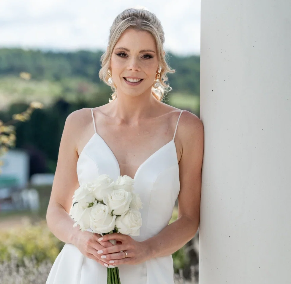 Pia posiert in ihrem eleganten Brautkleid mit Brautstrauß.