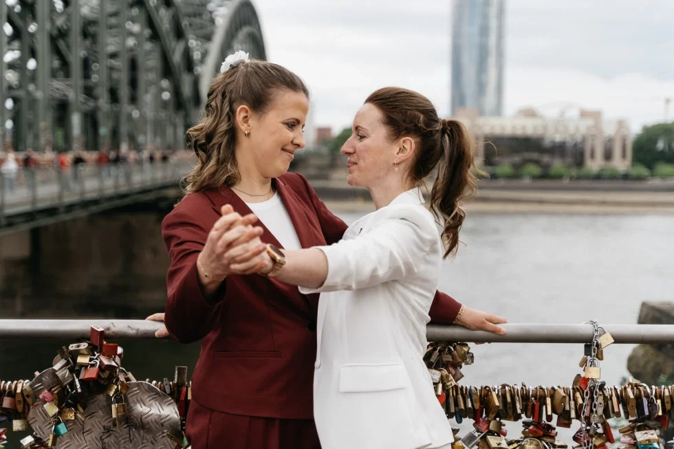 Michaela und Jessy teilen einen innigen Moment an der Kölner Brücke.