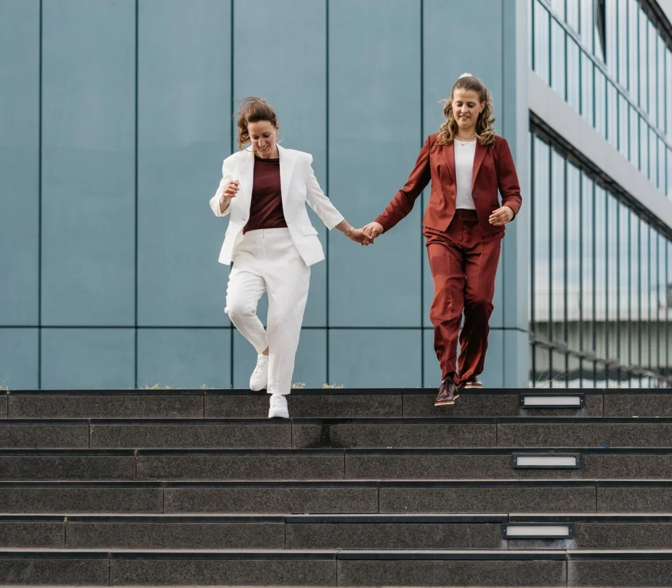 Michaela und Jessy schreiten eine Treppe gemeinsam hinunter.