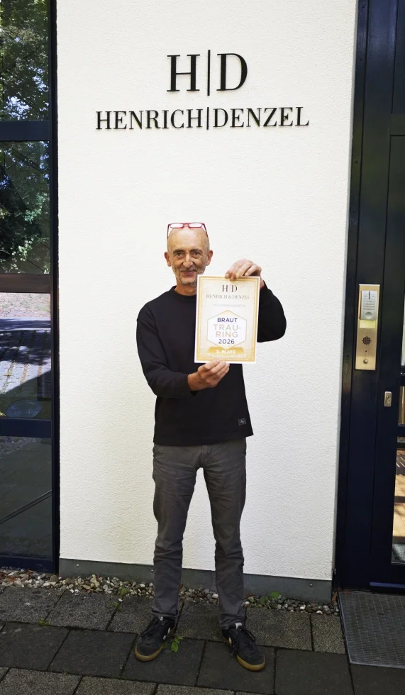 Jean Paul Callau, Dipl. Designer bei Henrich & Denzel, präsentiert die Urkunde für den 3. Platz beim „Trauring des Jahres 2026“.